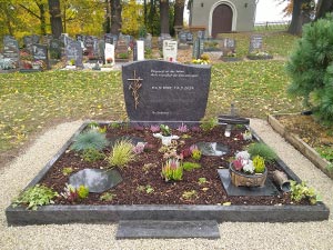 Doppelgrabmal bepflanzt mit Kreuz aus Naturstein